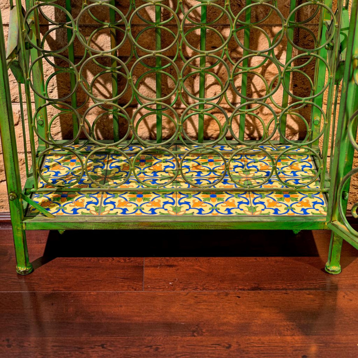 Bottom section of the wine cabinet showing circular bottle openings above a colorful tiled shelf.