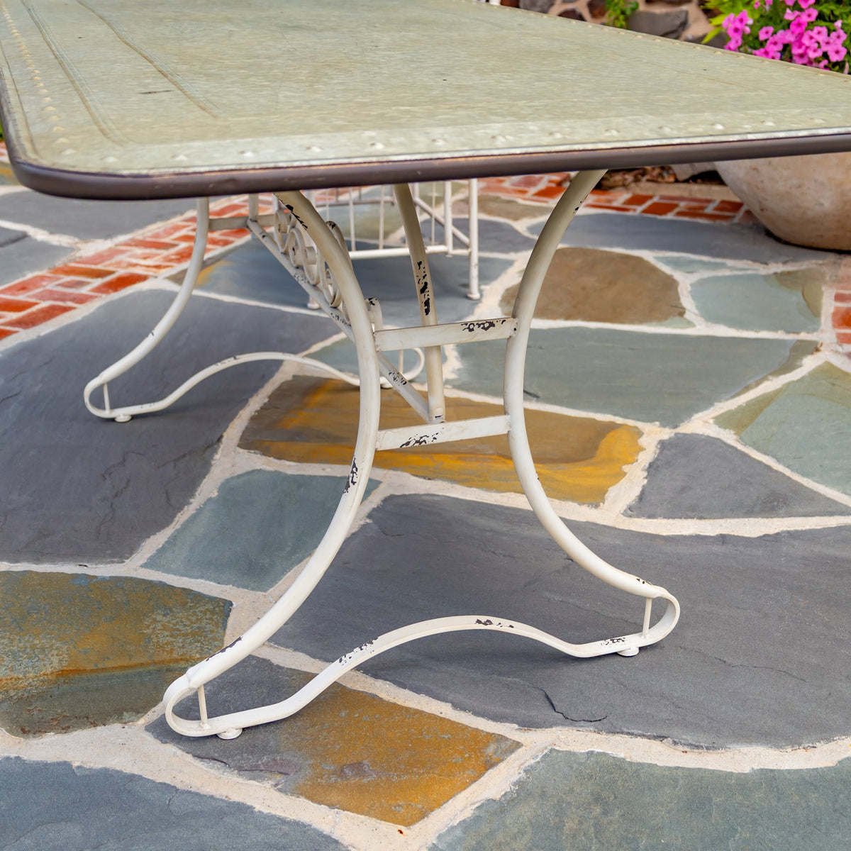 Side view of curved white metal table legs with distressed patches beneath the tabletop.