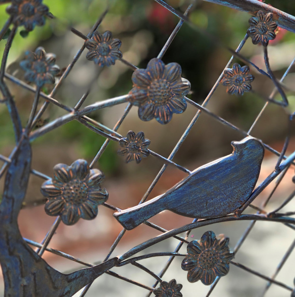 Close-up of a bird silhouette among raised flower ornaments and intersecting metal rods on the backrest.