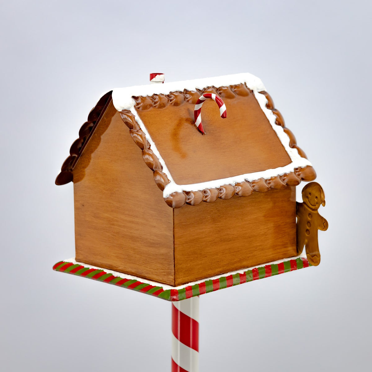 Back and side of the gingerbread mailbox, with a candy cane decoration and gingerbread figure beside it.