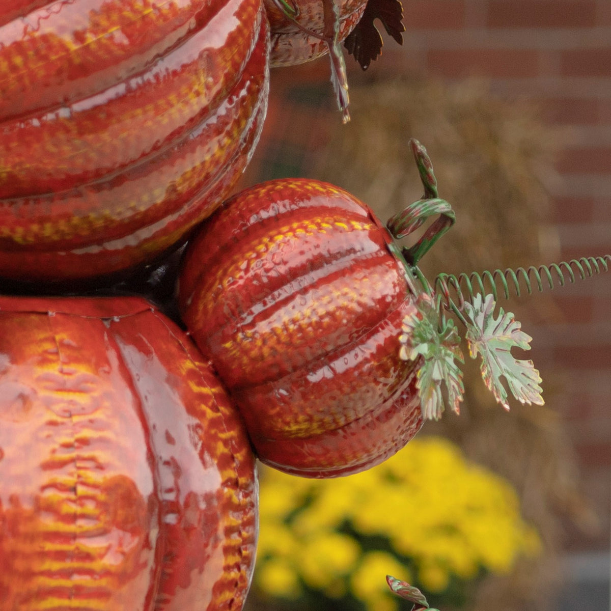 Close-up of a small striped orange pumpkin with a curled stem and decorative green leaves.