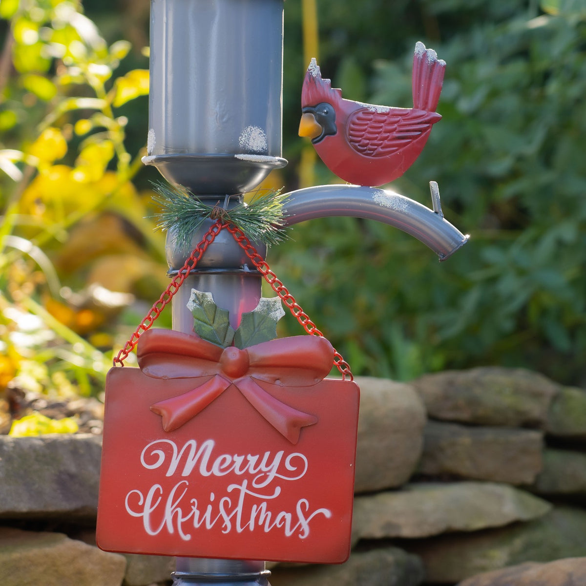 Close-up of a red cardinal above a hanging red sign with a bow and holly, attached to the pump.