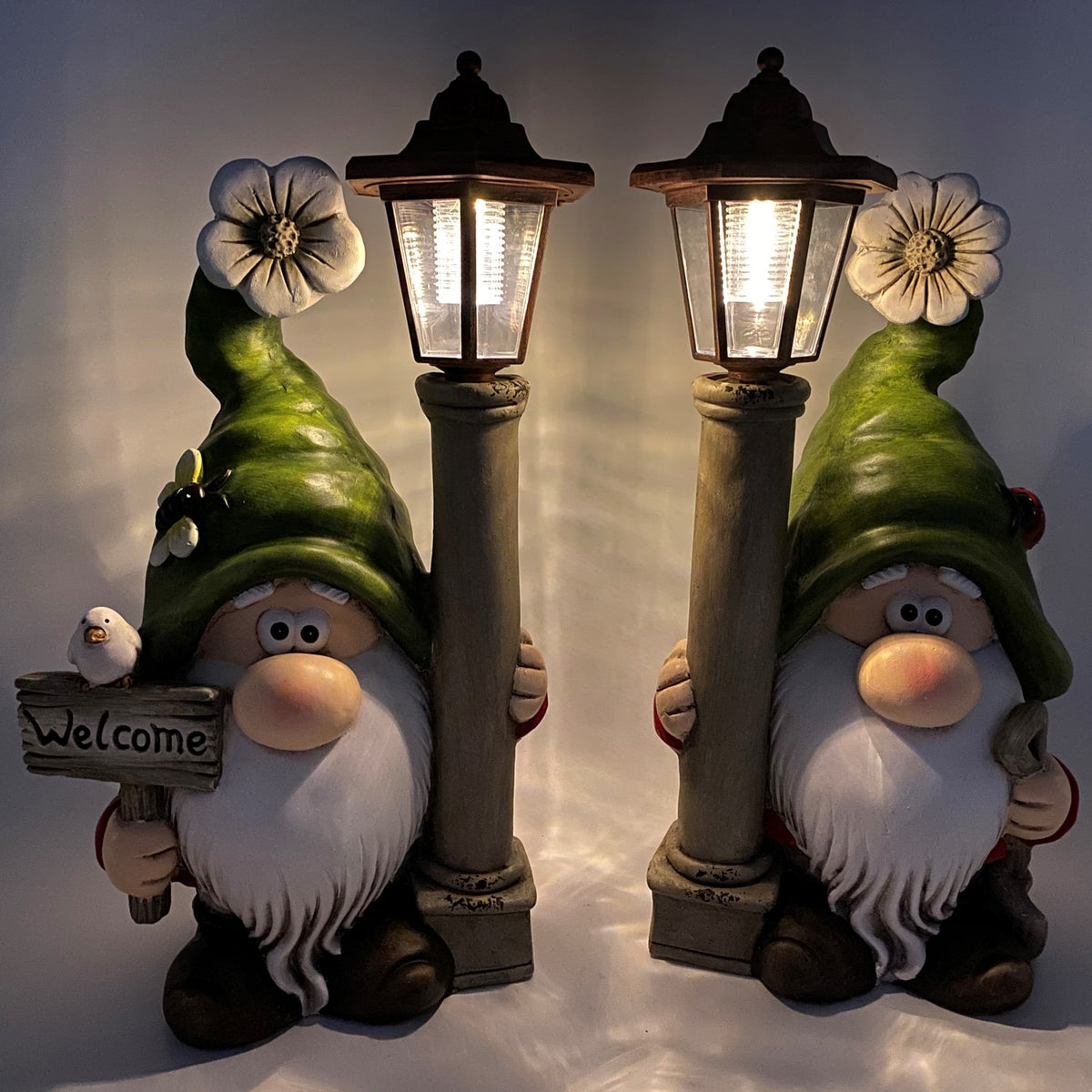 Two bearded garden gnomes hold glowing lanterns beside a small bird and flower details.