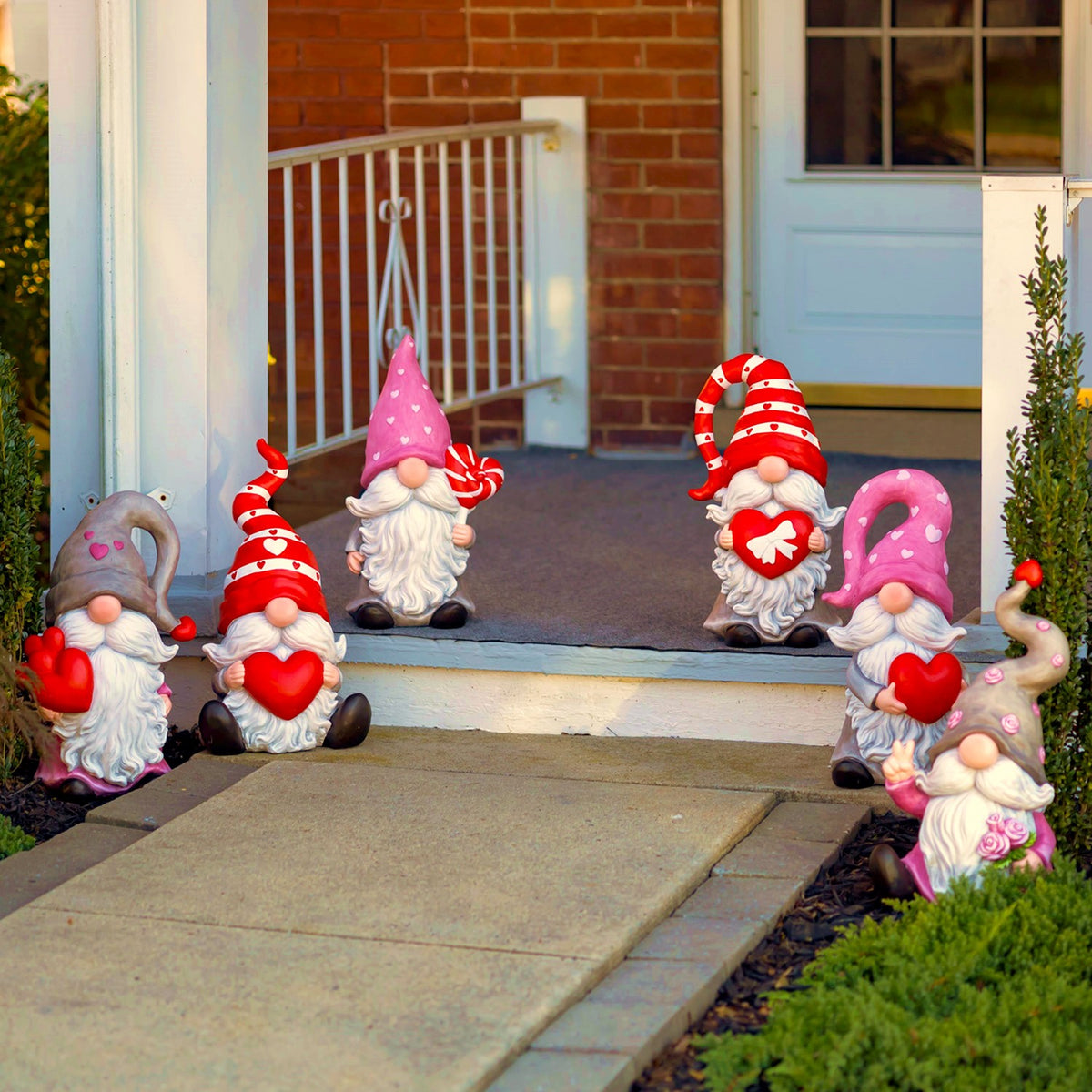 Six heart-themed gnome statues displayed along a front porch and walkway.