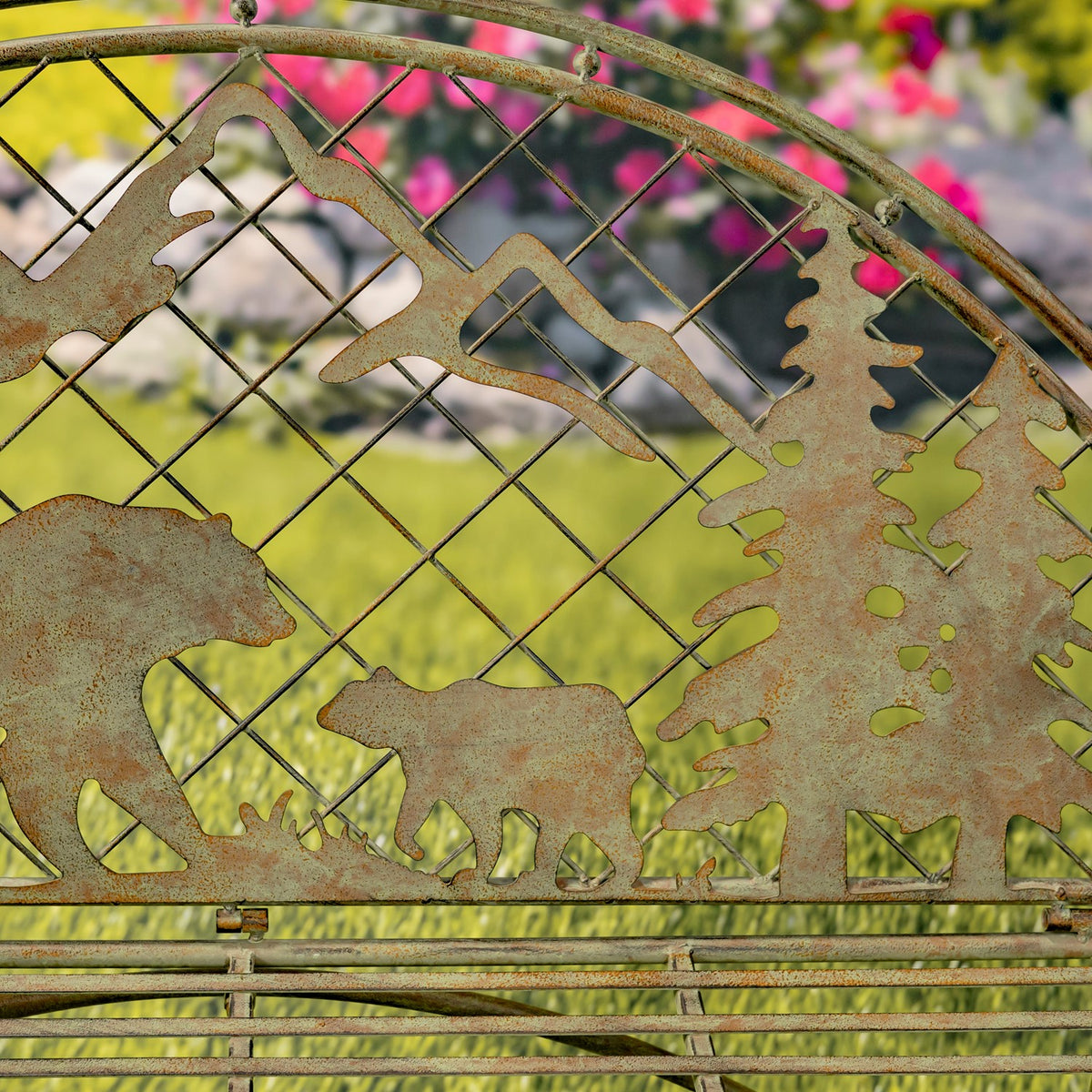 Close view of mountain, bear, and evergreen silhouettes across the bench’s metal back.
