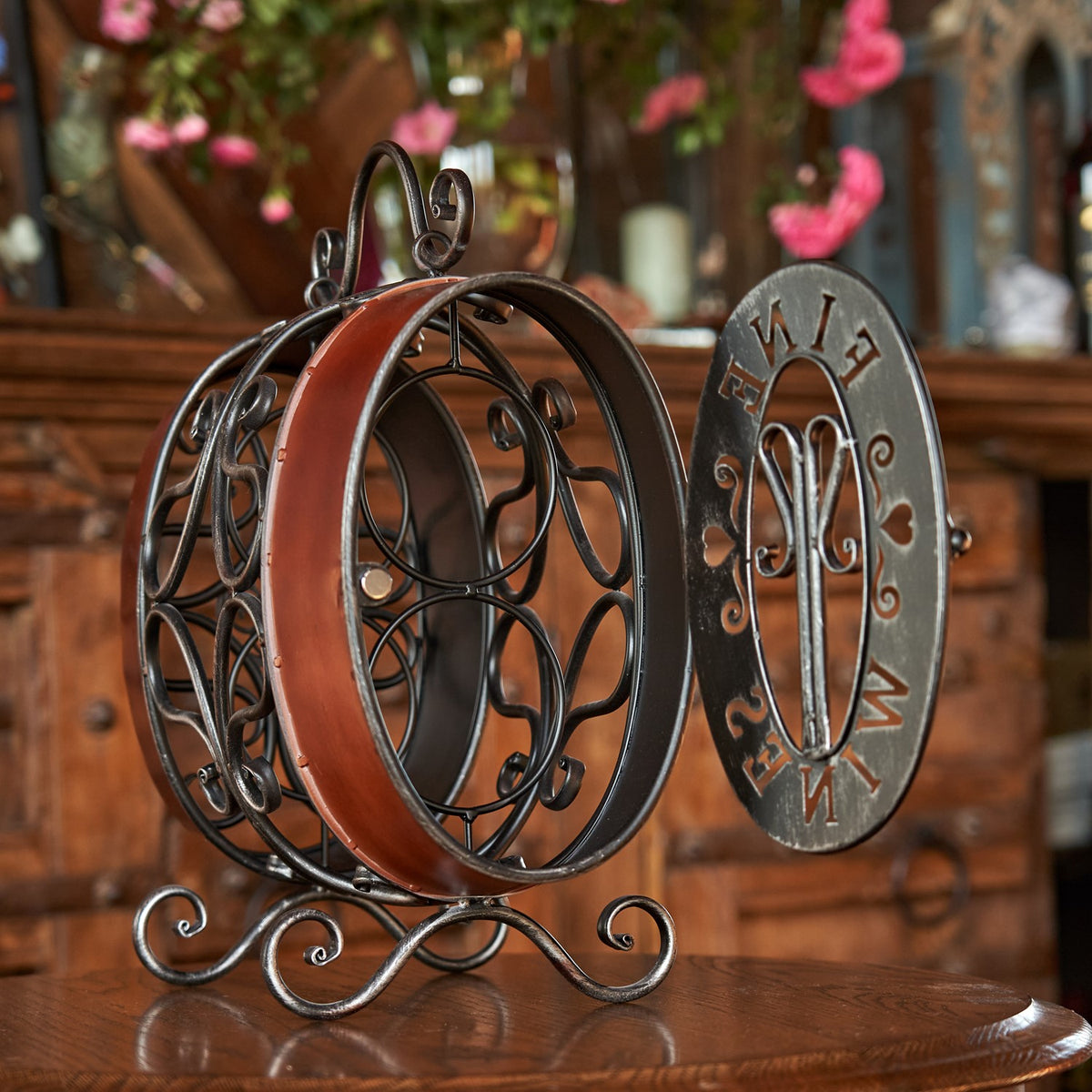 Open wine rack with circular metal bottle holders and its decorative oval front panel set beside it.