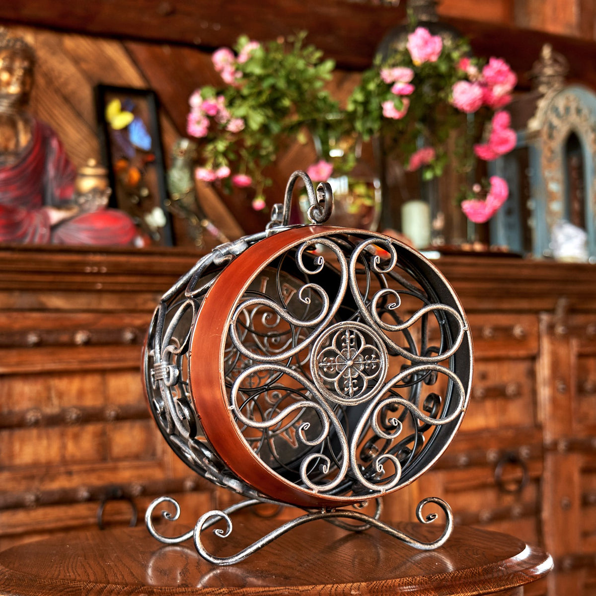 Wine rack facing forward, showing its circular scrollwork panel, arched handle, reddish-brown band, and curved base.