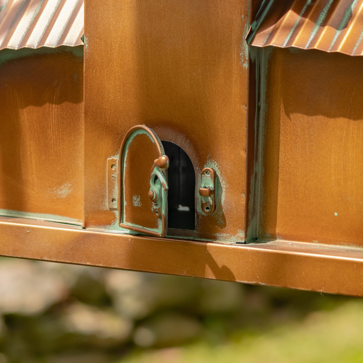 Close-up of a small arched metal door beside a dark opening on the birdhouse.