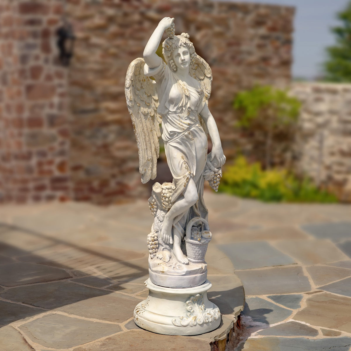 Full view of the winged angel statue standing on a decorated round base.