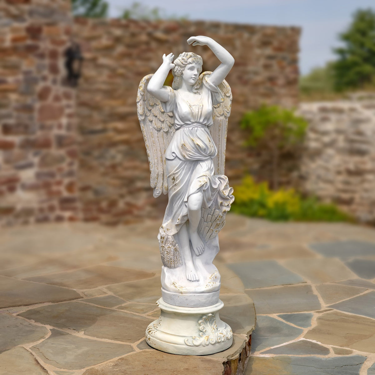 Full view of the angel statue with raised arms, outstretched wings and flowing robes.