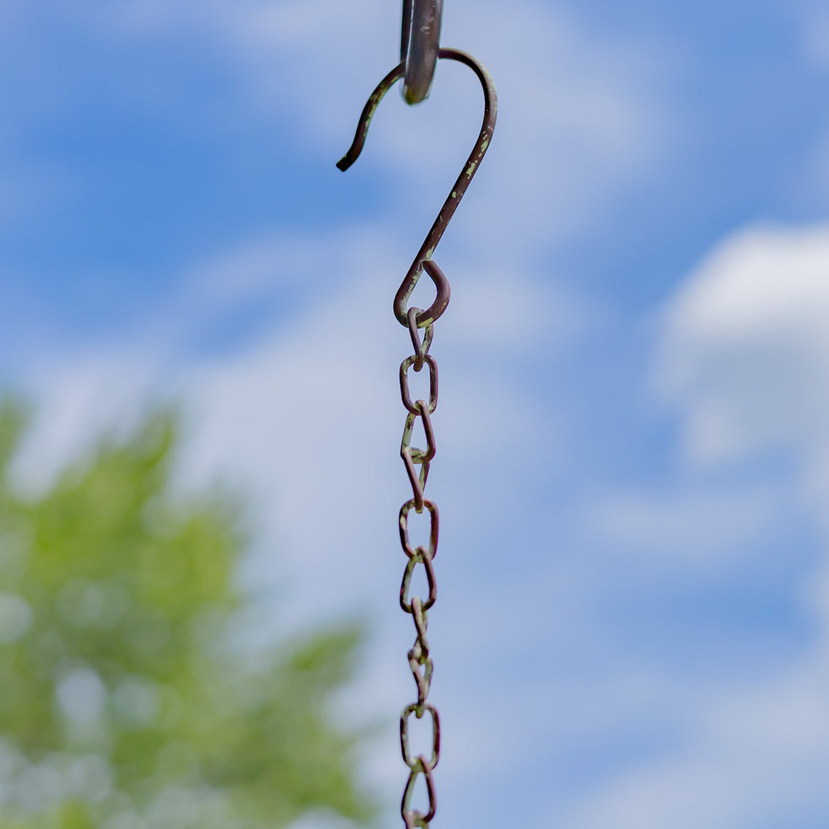 Close-up of the metal hook and linked chain against a blue sky.