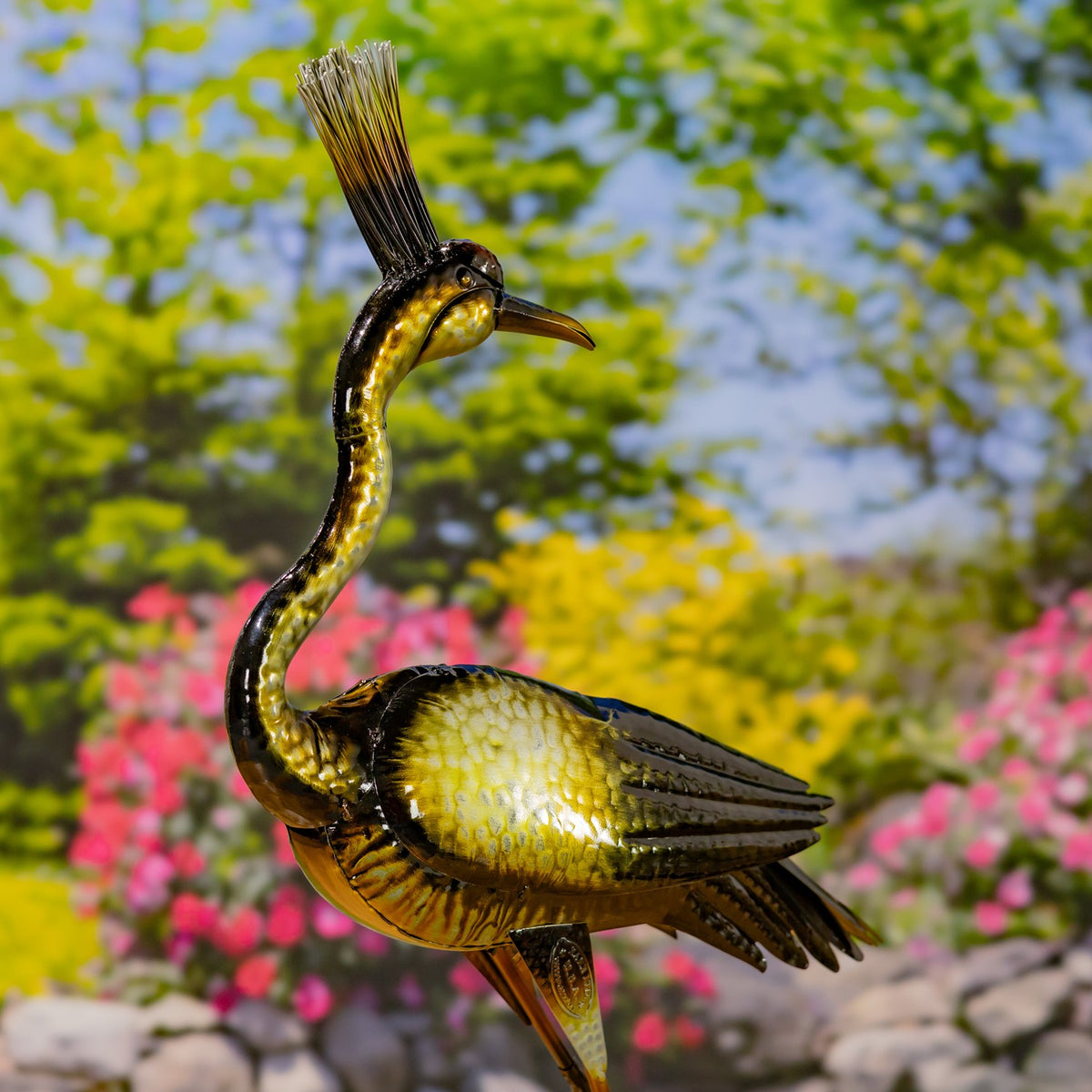Metallic heron figurine in profile, showing its slender curved neck, plume crest, and folded wings.
