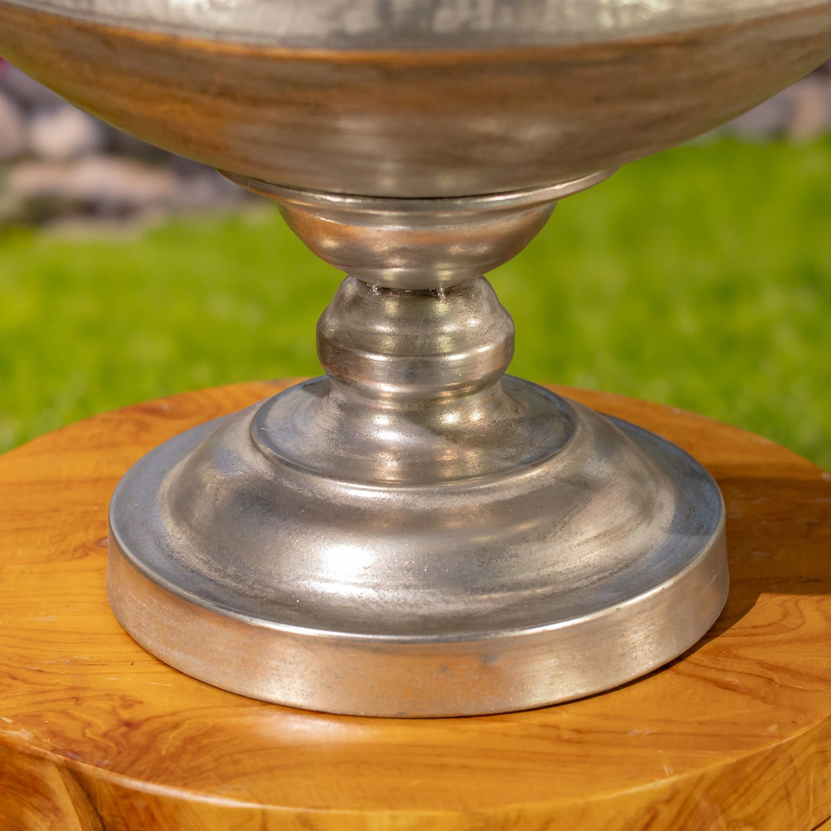 Close-up of the urn’s rounded pedestal base resting on a wooden stand.