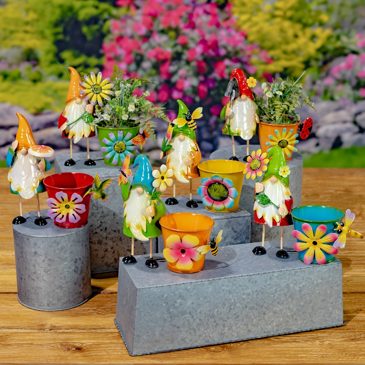 Colorful gnome figures and flower-decorated pots arranged on gray pedestals outdoors.