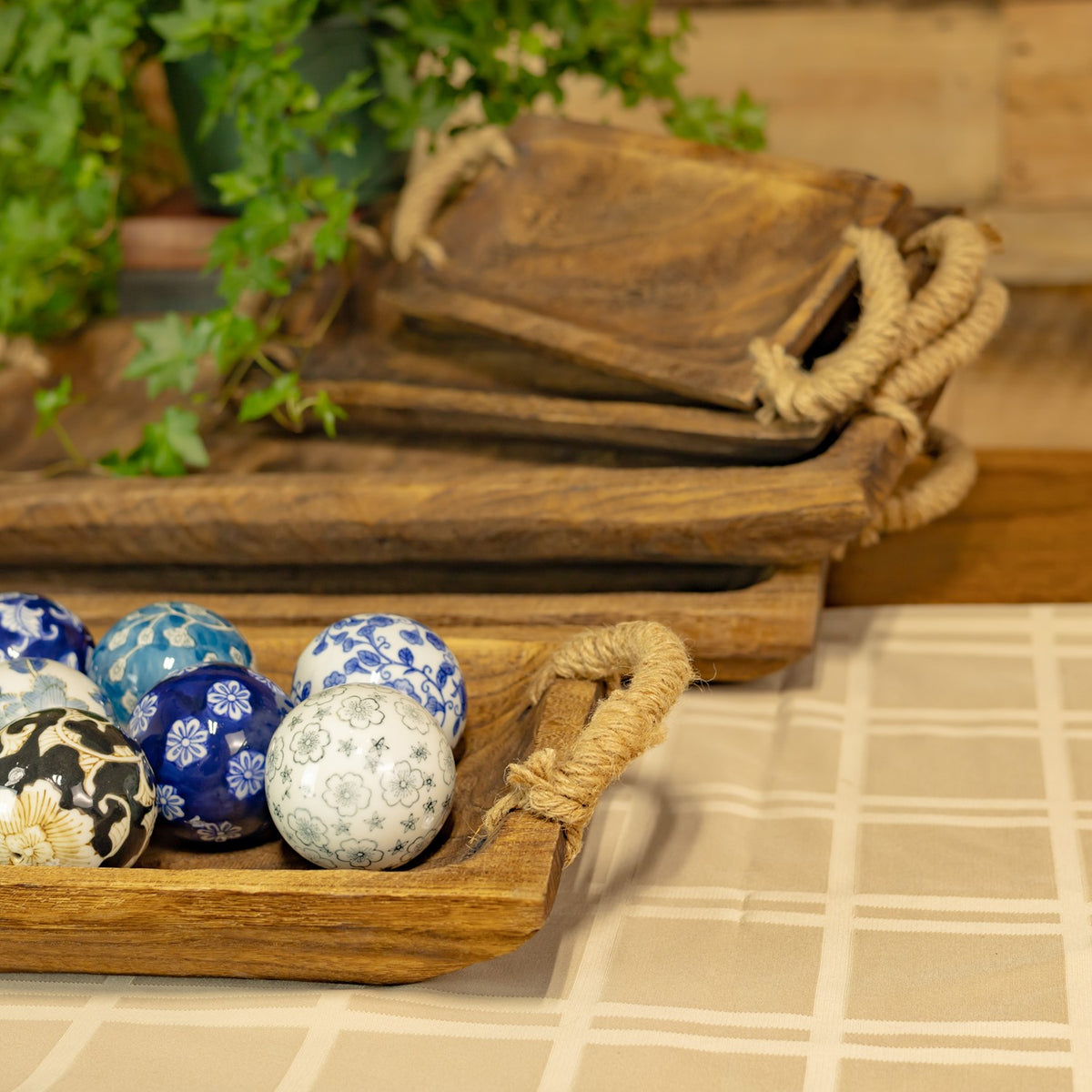 Close view of the wooden tray edges and coarse rope handles beside patterned spheres.