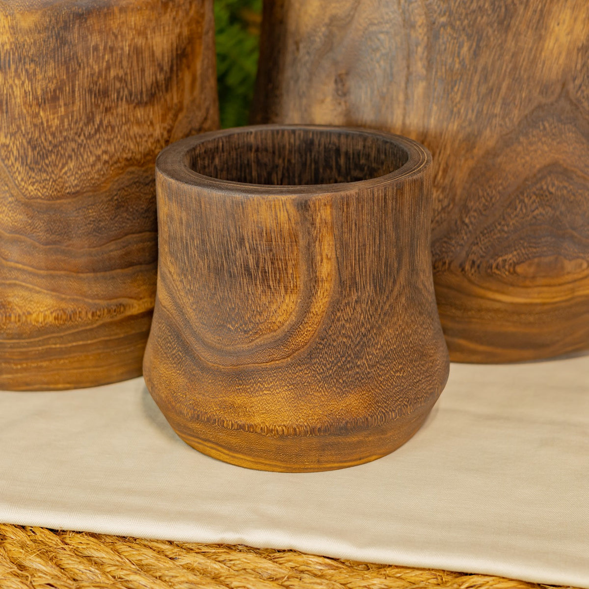 Close-up of the smallest wooden bowl with a dark interior and curved golden-brown grain.