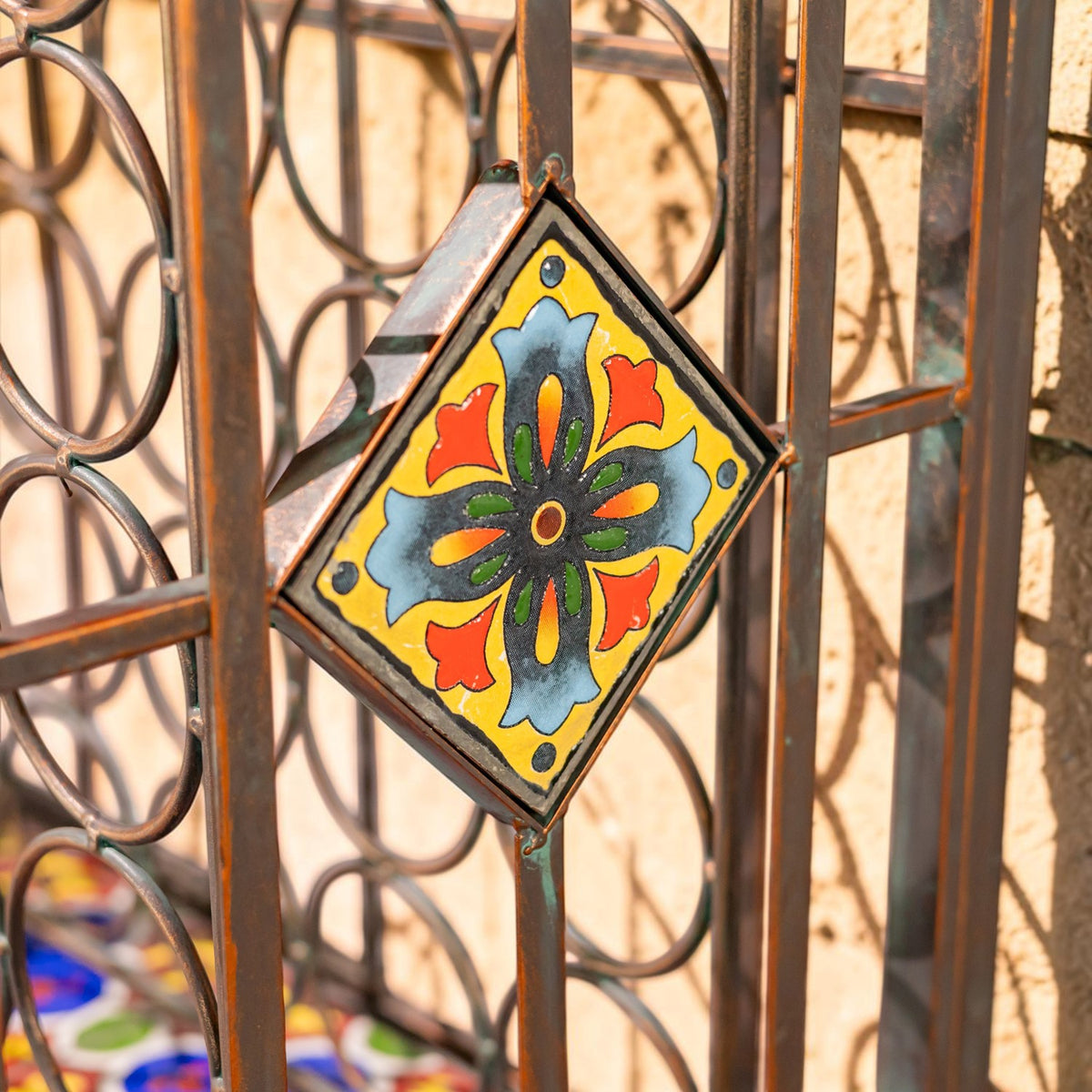 Close-up of a colorful floral tile set into the rack’s iron frame.