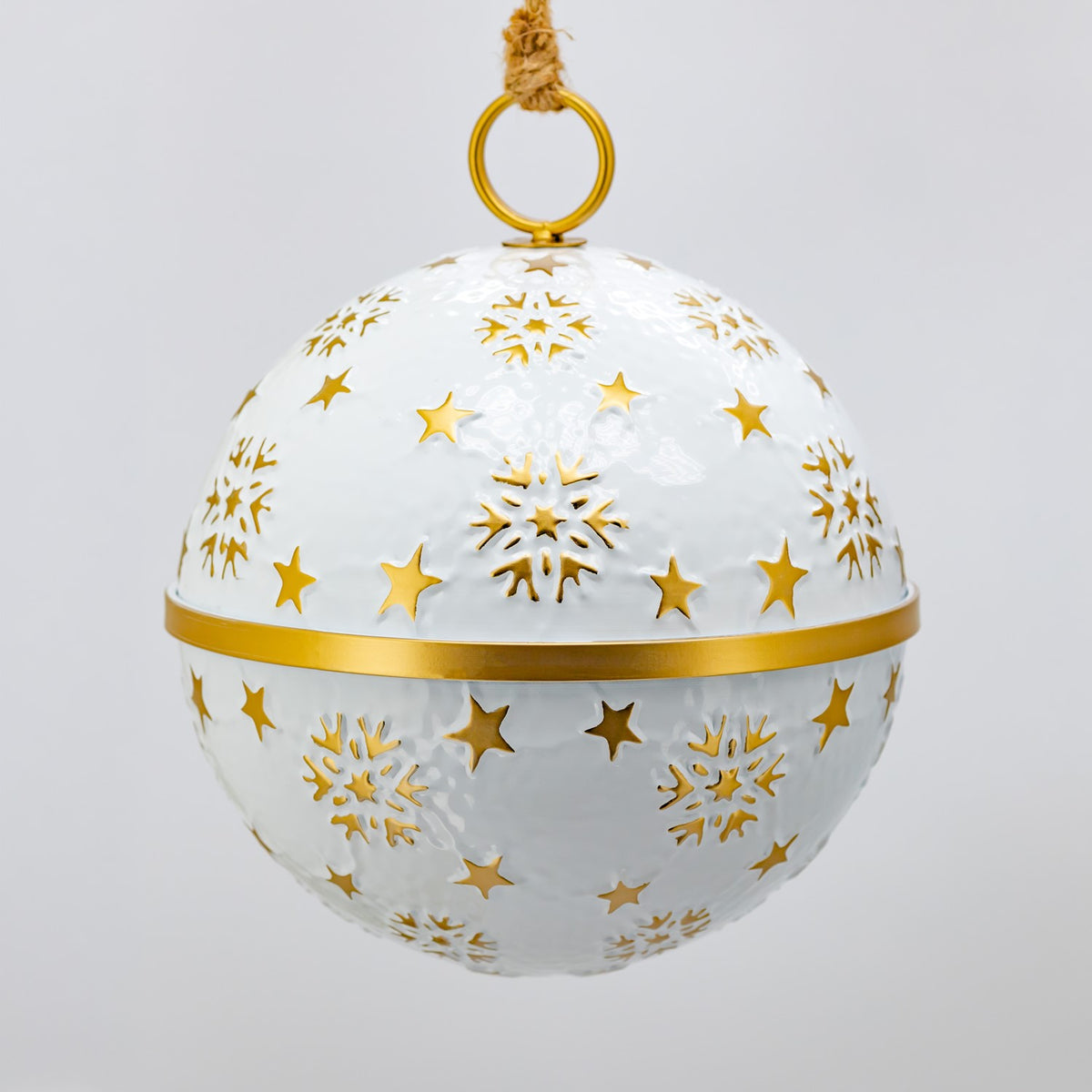 One round white ornament hangs from a gold ring, decorated with gold stars and snowflake shapes.