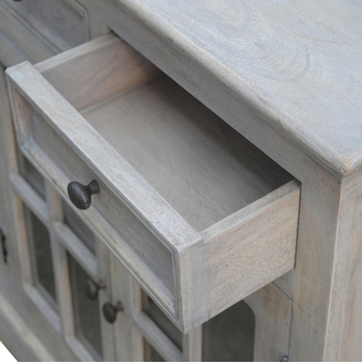Close-up of an open sideboard drawer showing its wood interior and round knob