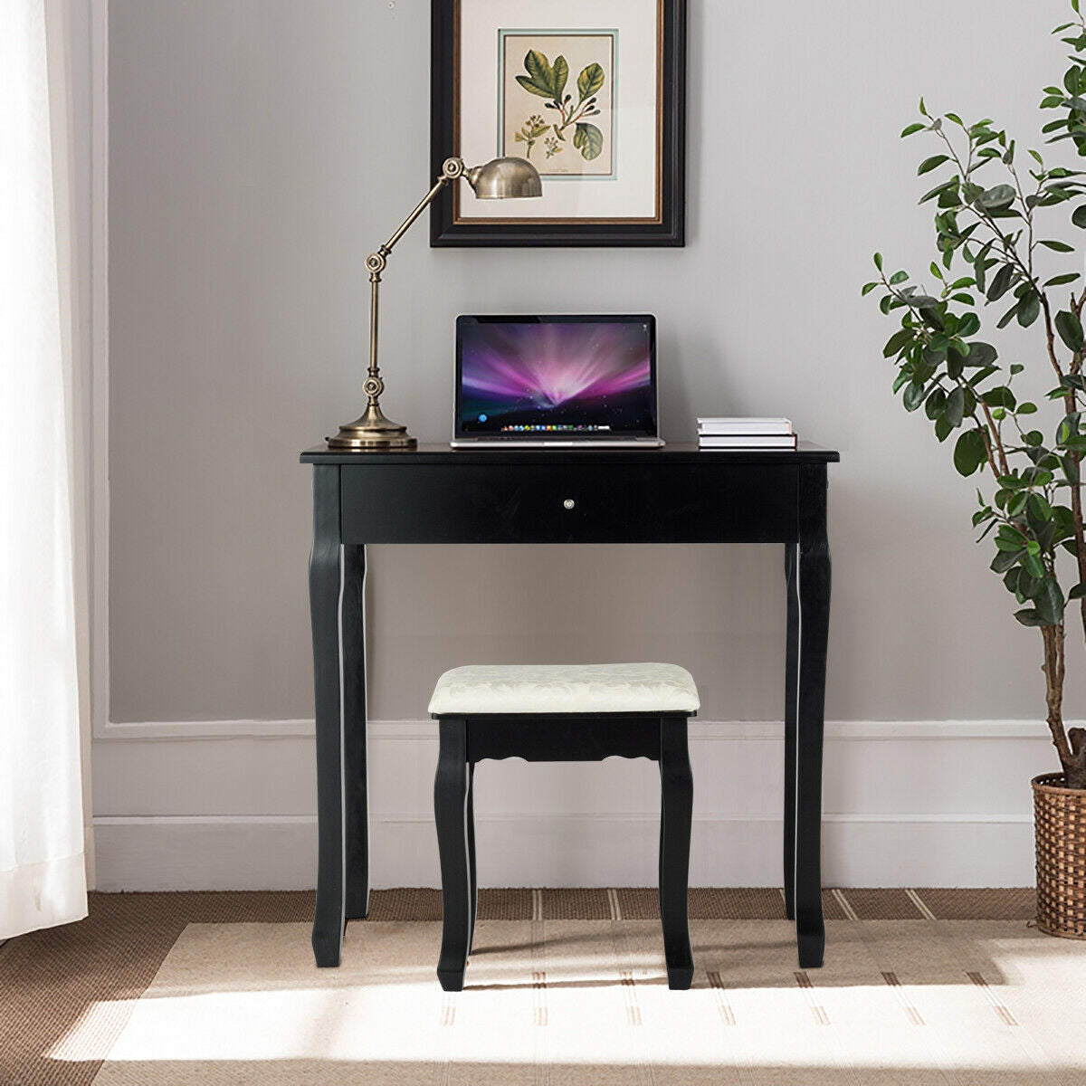 Black desk with a white-cushioned stool, styled with a lamp, laptop, and books; no mirror is visible.