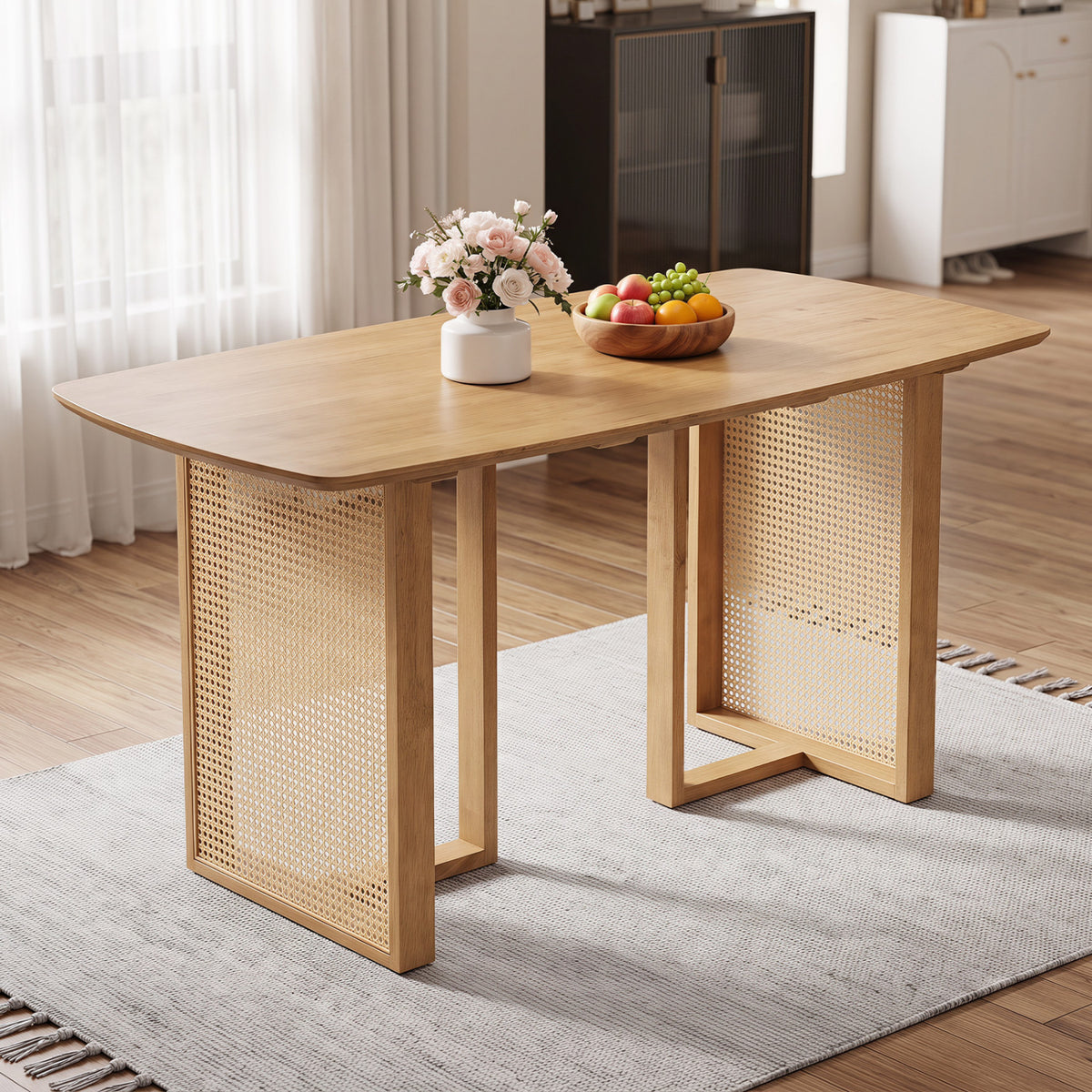 A light wood dining table with woven panel legs sits on a rug beside a bright window.