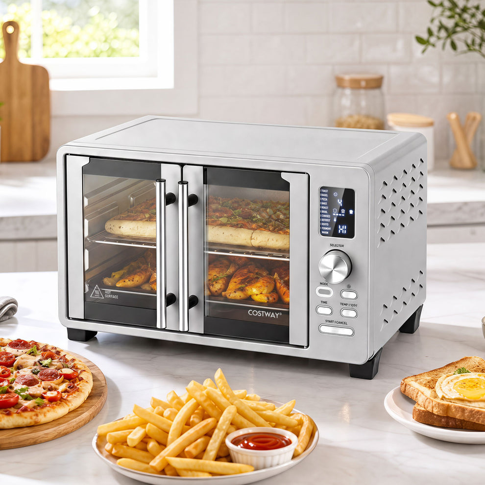 Silver toaster oven with French doors on a counter, with pizza, fries, and toast nearby.