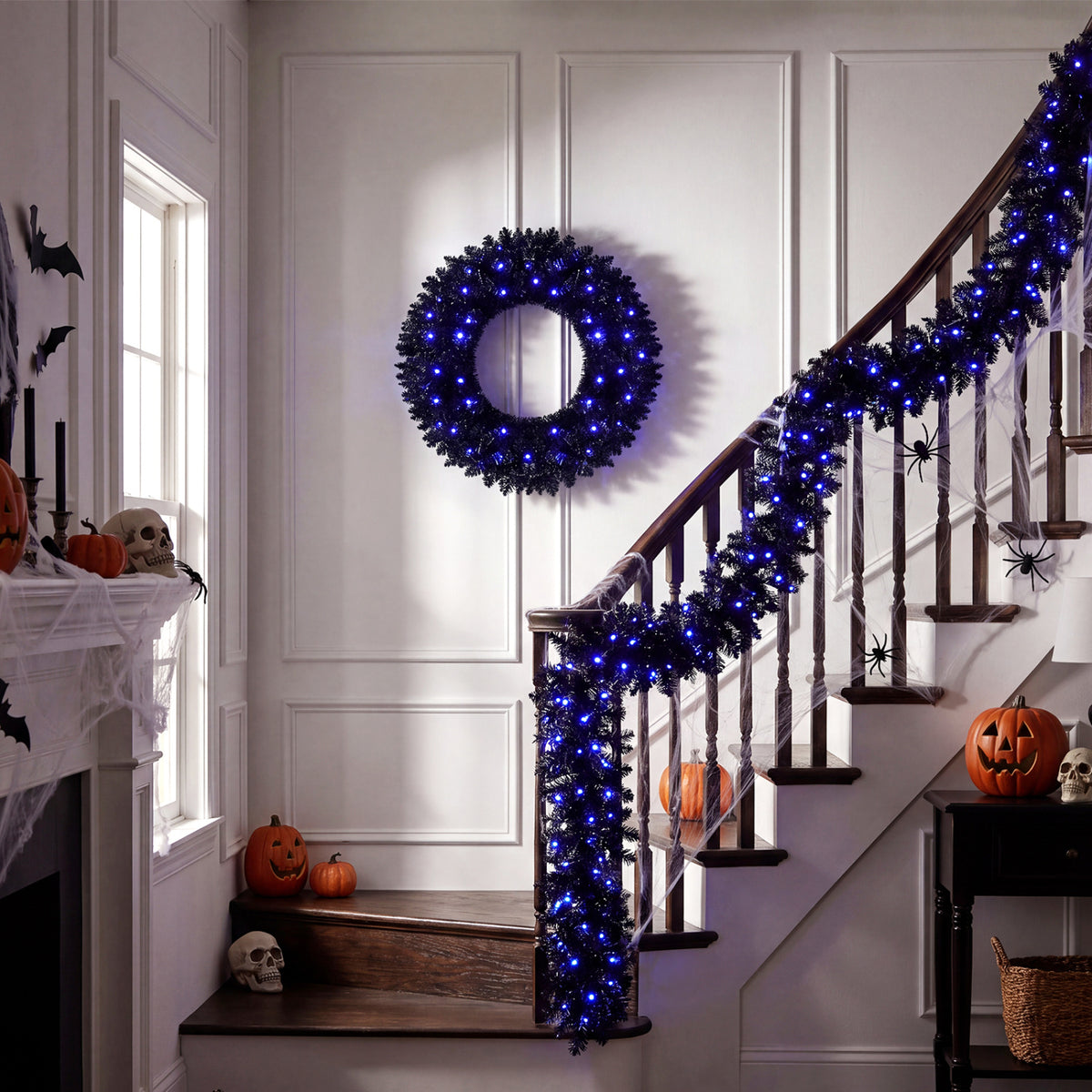 Blue-lit black wreath hangs on a paneled wall as matching garland wraps a staircase decorated for Halloween.
