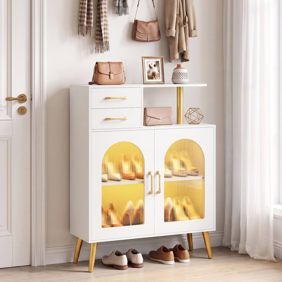 White cabinet with glowing amber doors styled in an entryway beneath coats and bags.