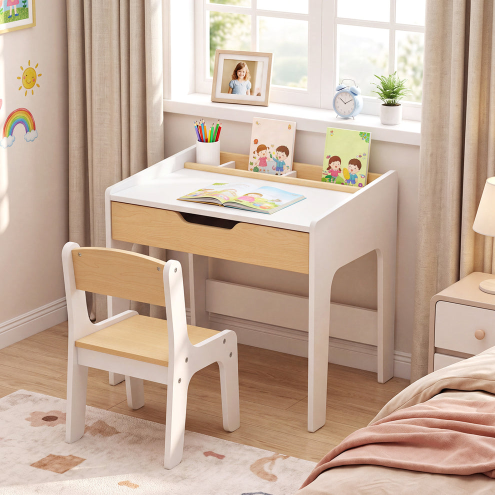 White and light wood children’s desk and chair set beside a window, with books and pencils on the desk.