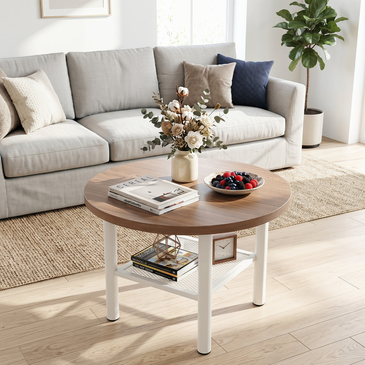 Round coffee table styled with books and a fruit bowl in front of a light sofa.