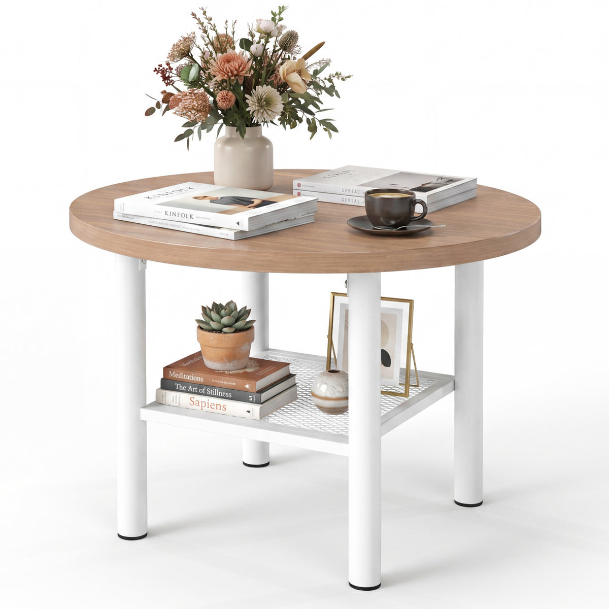 Round coffee table holding flowers and books, with a plant and framed pictures on its lower shelf.