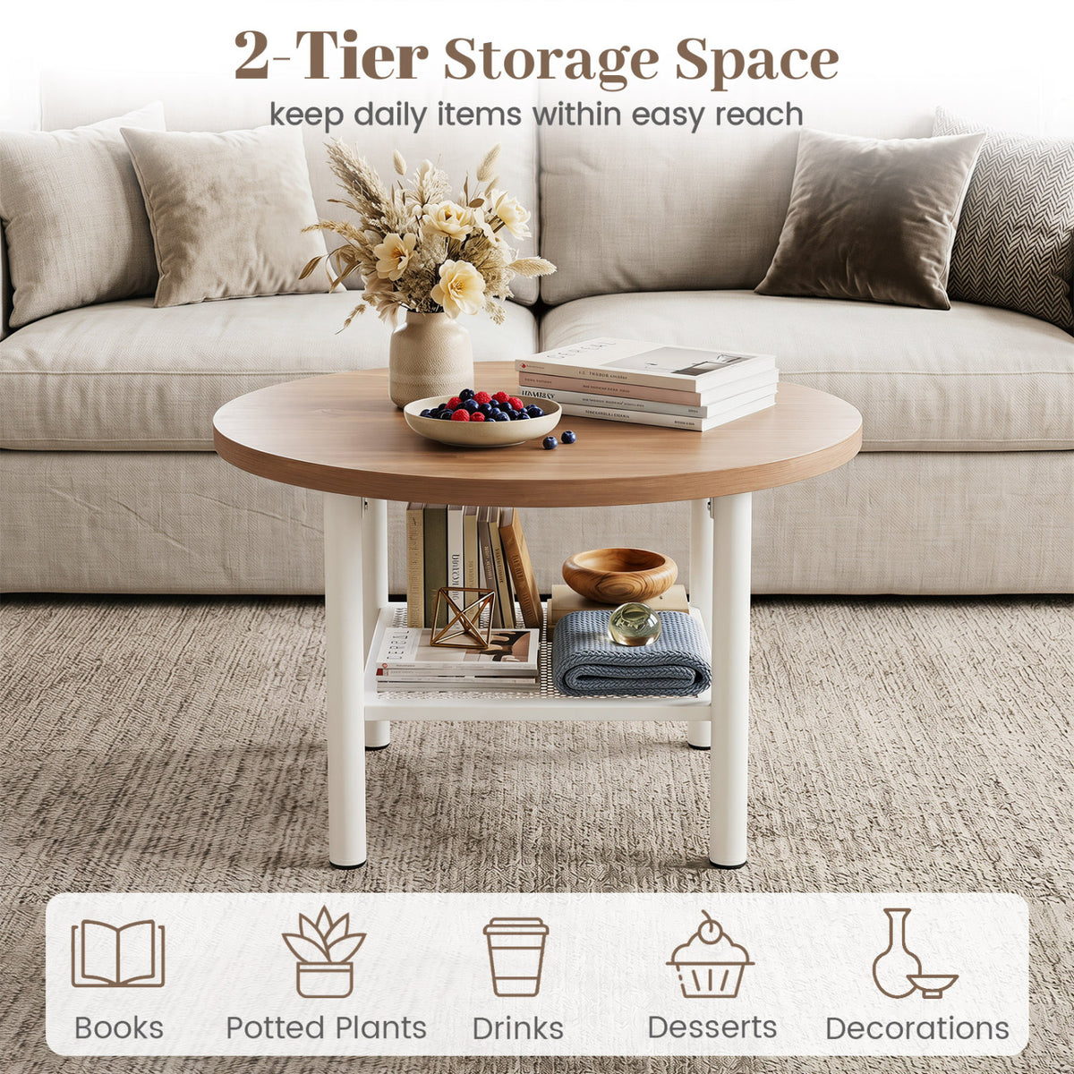Round coffee table with a white metal frame and lower shelf holding books and folded fabric, in front of a sofa.