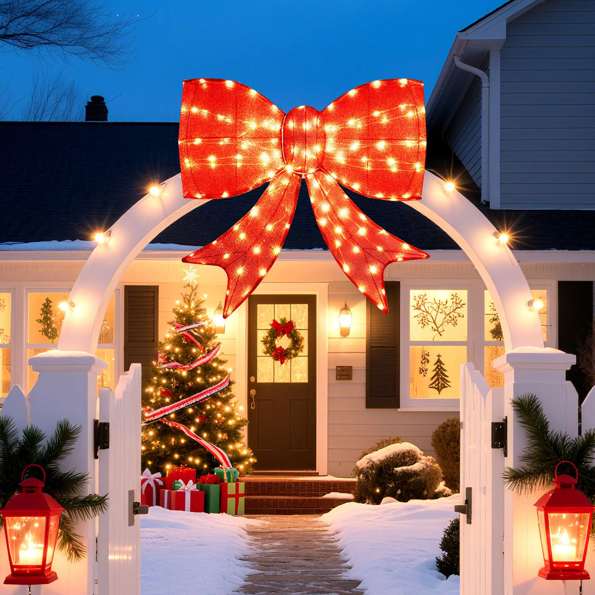 Large glowing red bow hangs above a snowy front gate, with a decorated Christmas tree by the house entrance.