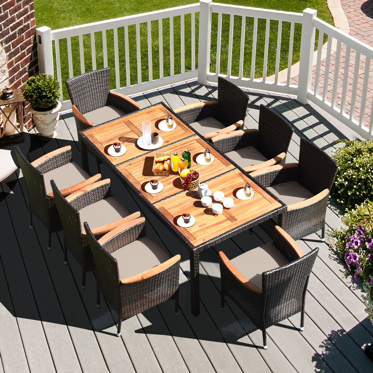 A slatted wood dining table is set with dishes and surrounded by woven chairs on a deck.