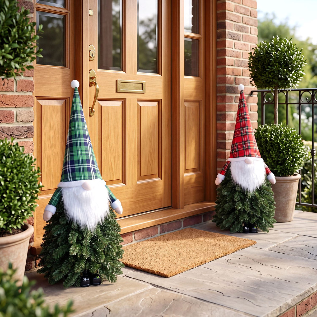 Two gnome-like tabletop trees with green and red plaid hats stand by a wooden front door.