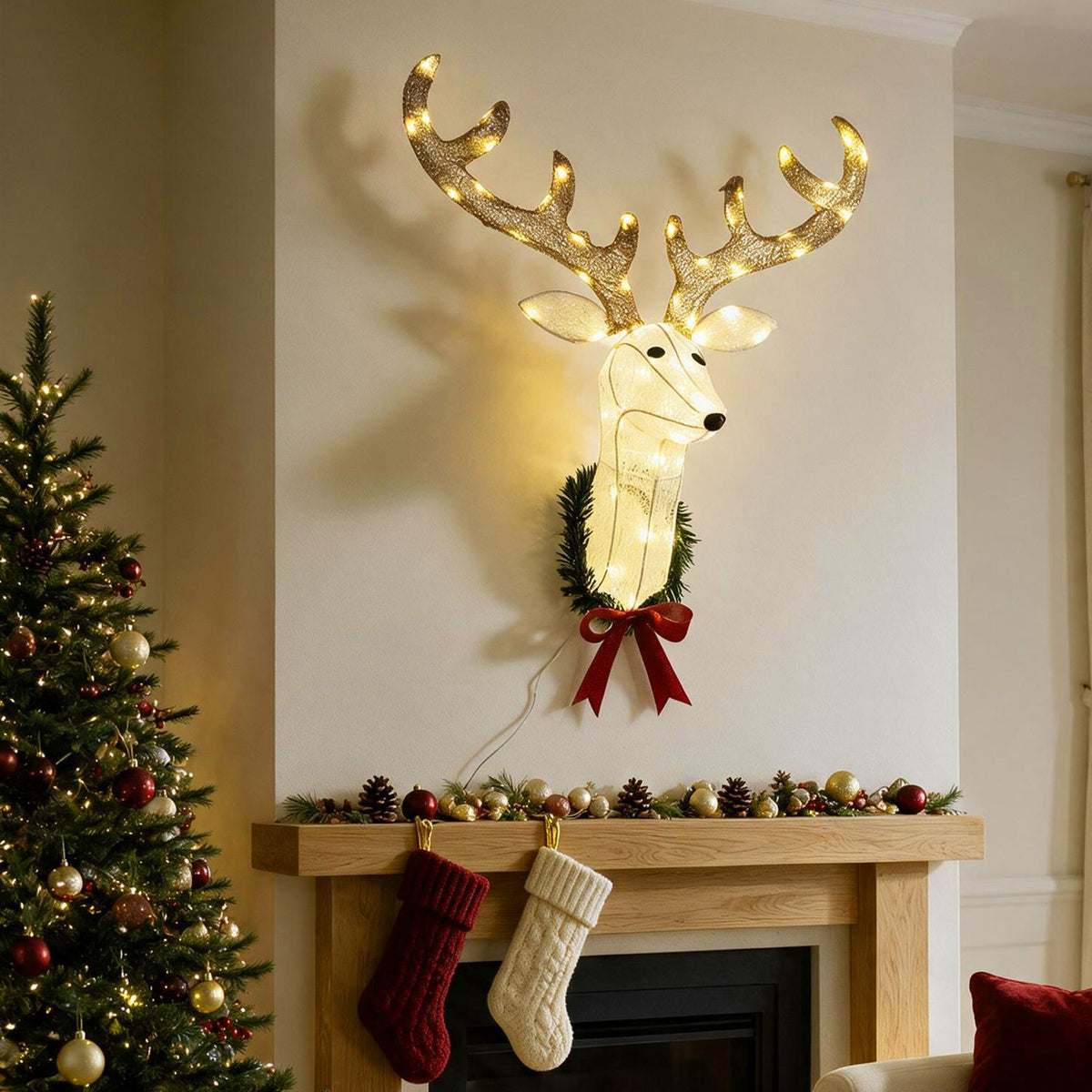 Illuminated reindeer head wreath hangs above a fireplace beside a decorated Christmas tree.