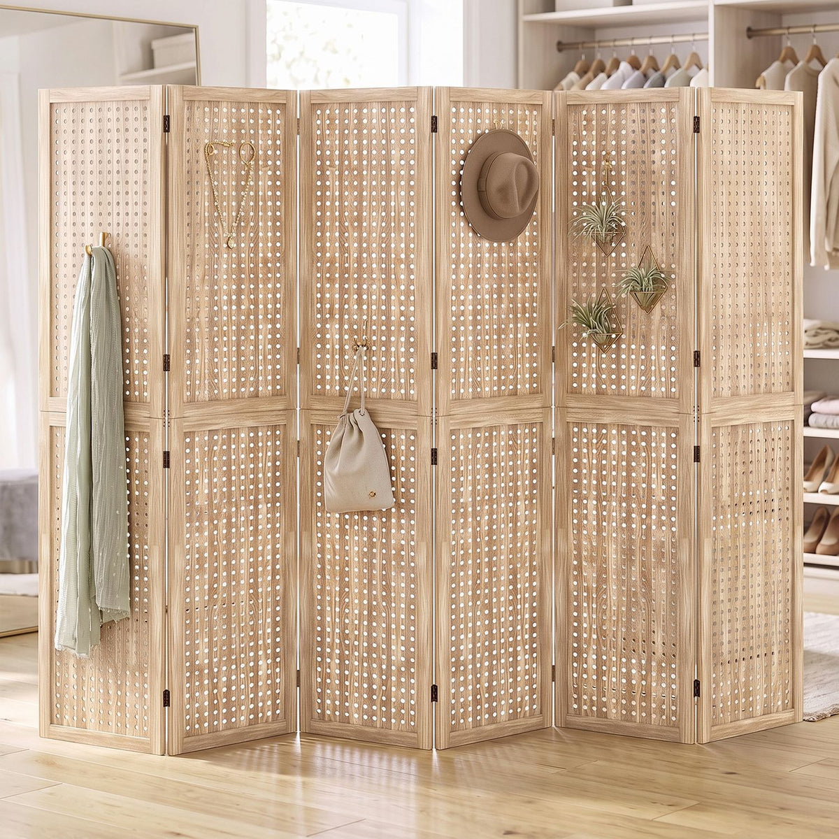 Light wood folding divider with perforated panels, decorated with hats, plants, a bag, and a hanging garment.