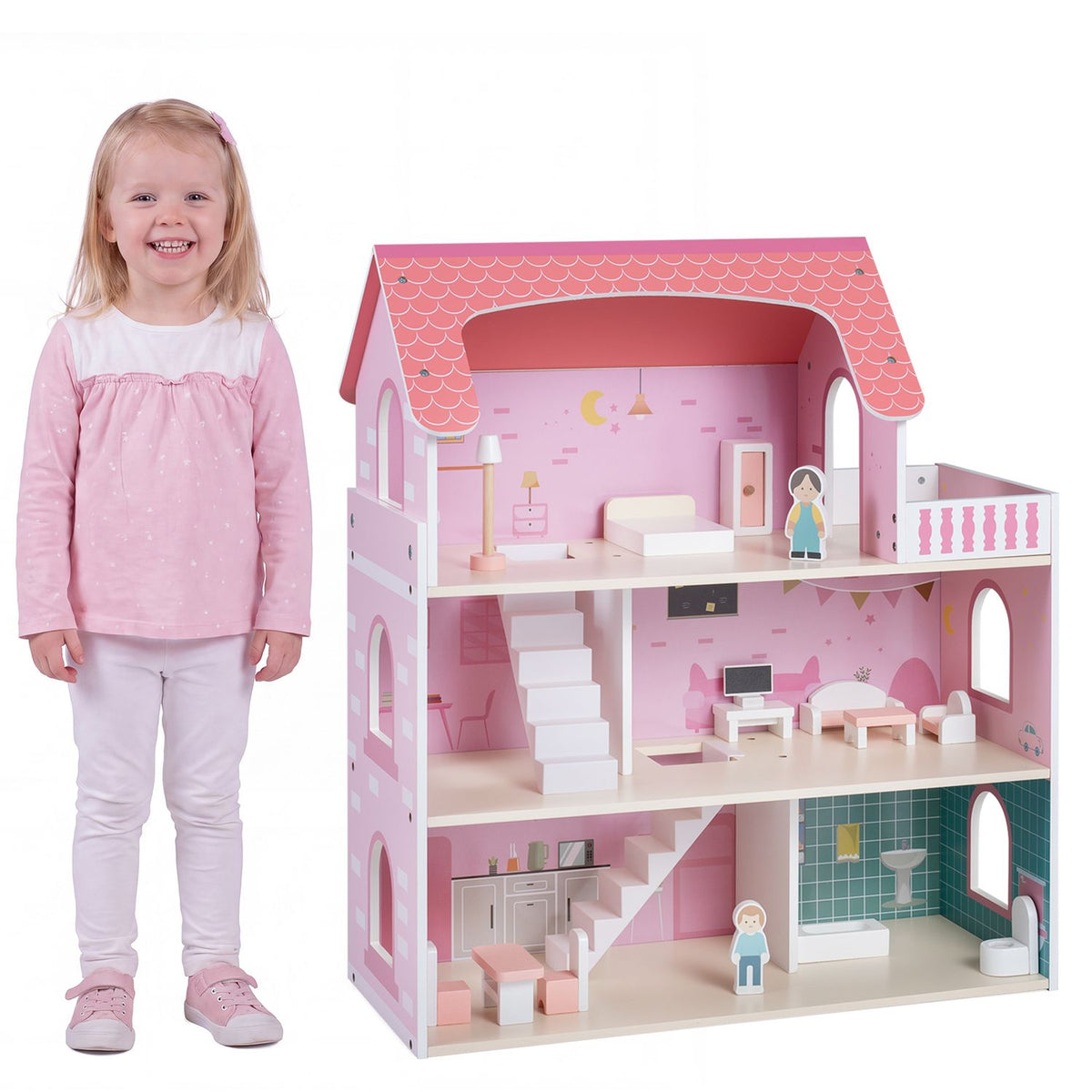 A child stands beside the pink furnished dollhouse against a white background.