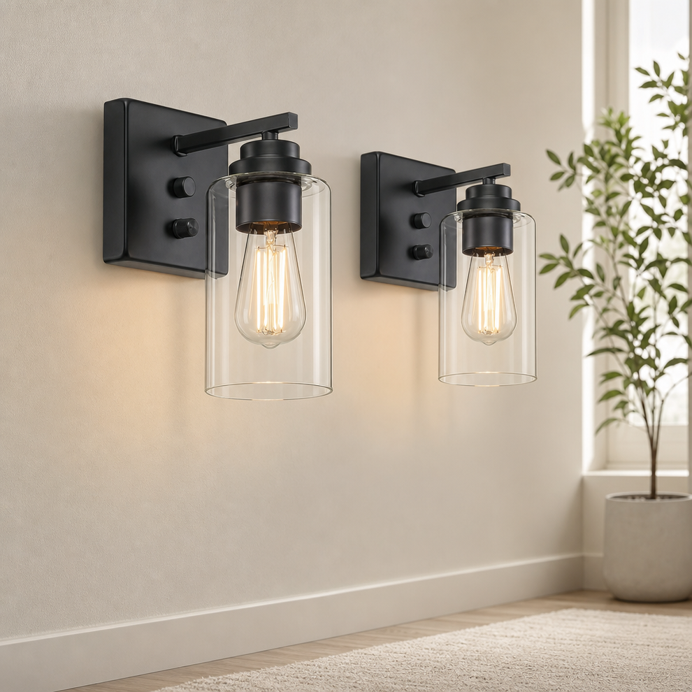 Matte black metal wall sconces set of two with clear cylindrical glass shades mounted on a light wall