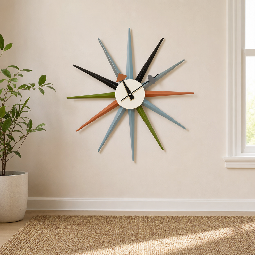 Multicolor mid-century sunburst wall clock on a light beige wall above a woven rug and potted plant