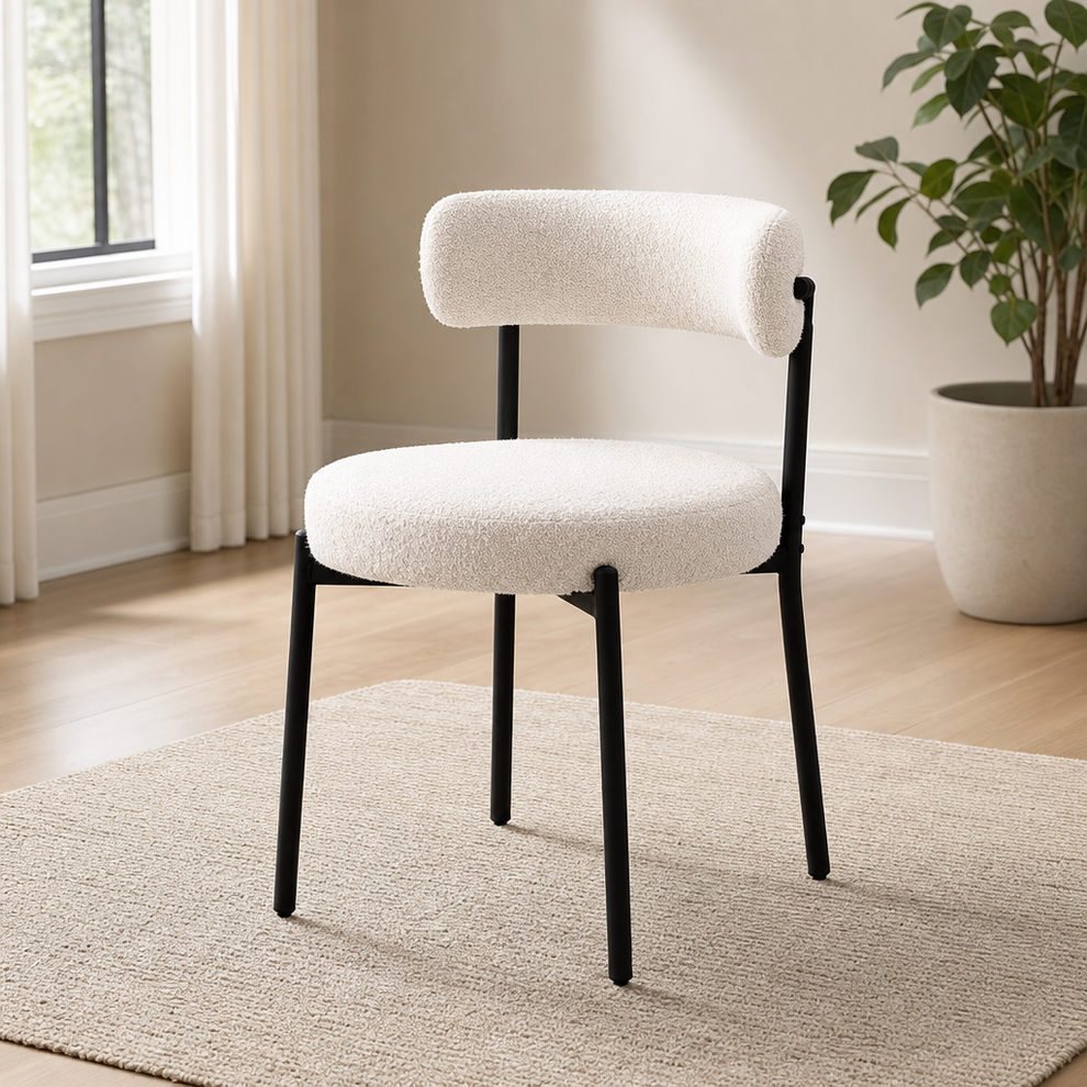 White boucle dining chair with curved back and matte black metal legs, angled front view on a rug.