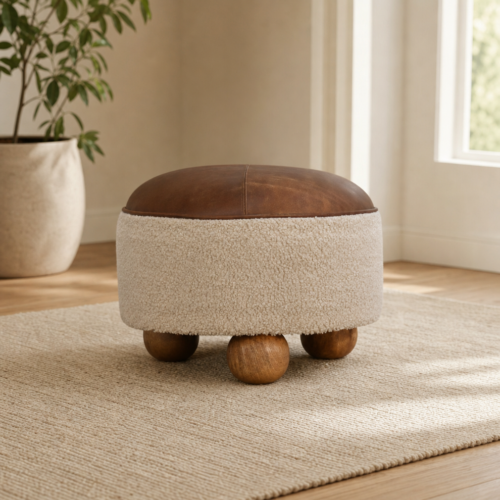 Round Boucle Footstool with Buffalo Hide Leather Seat centered in a warm neutral furnished room