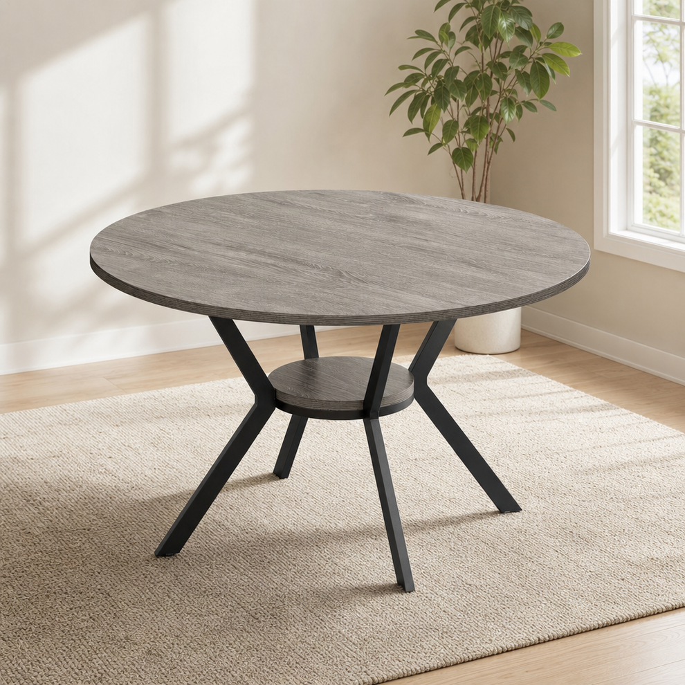Round dining table in gray finish with X-shaped black metal base and lower shelf, angled front view.