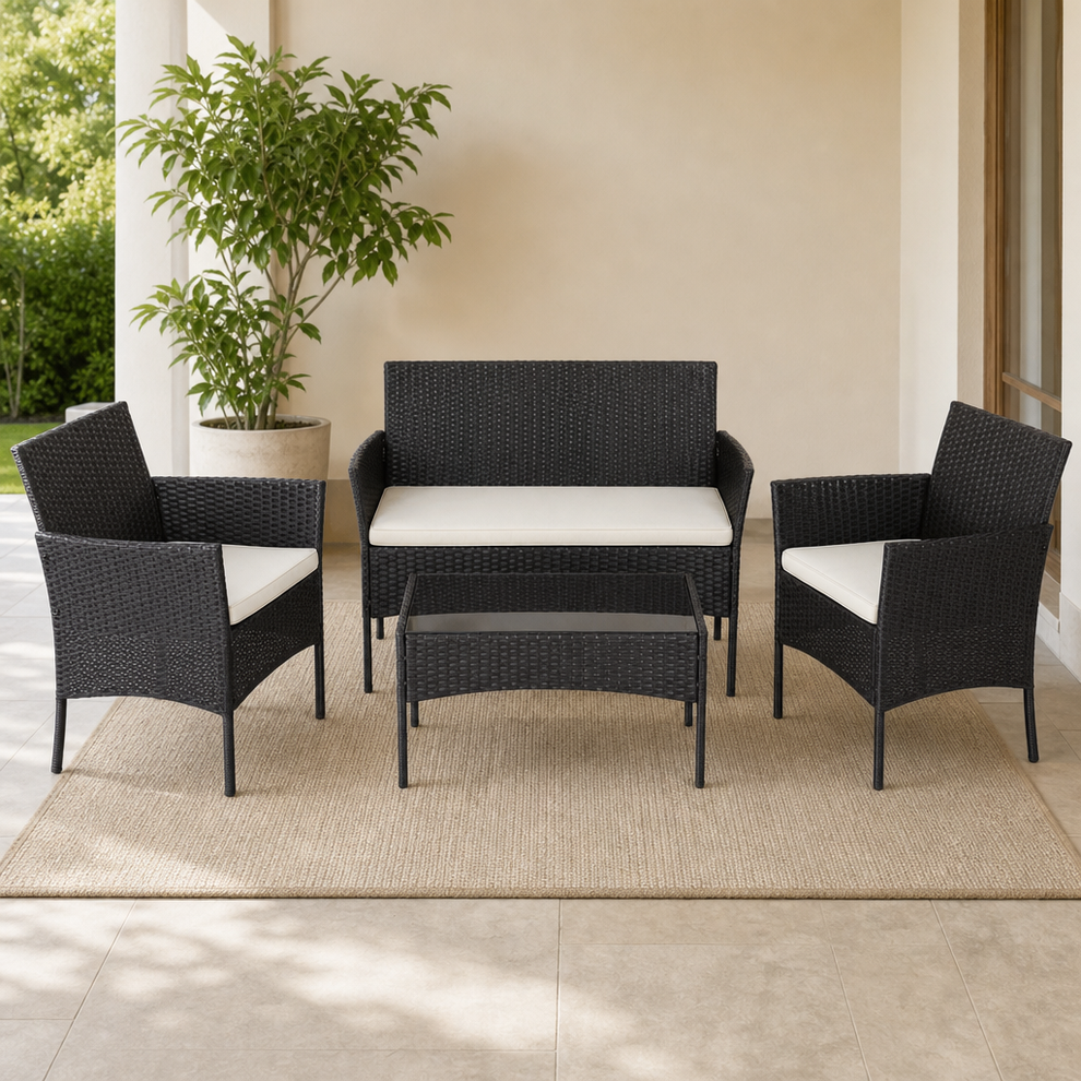 Black PE rattan 4-piece patio set with cream cushions front view on covered patio rug.