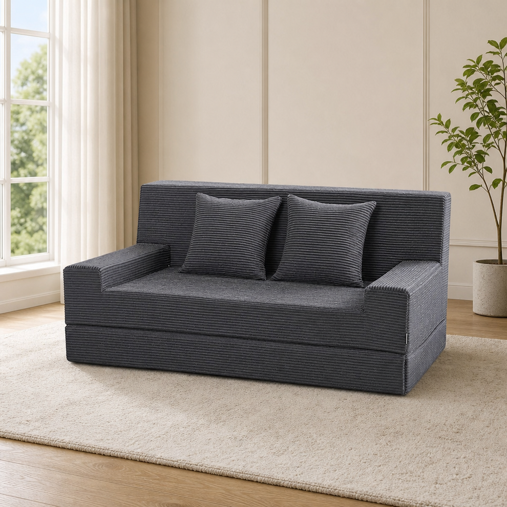 Grey corduroy loveseat sofa bed angled front view with two matching square pillows on a light rug