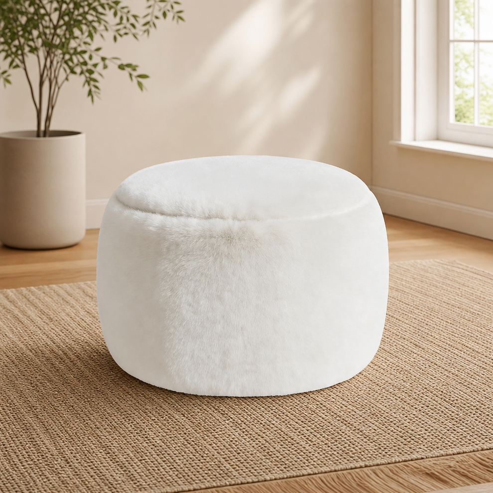 White faux fur round pouf on a woven rug near a potted plant and window, angled front view