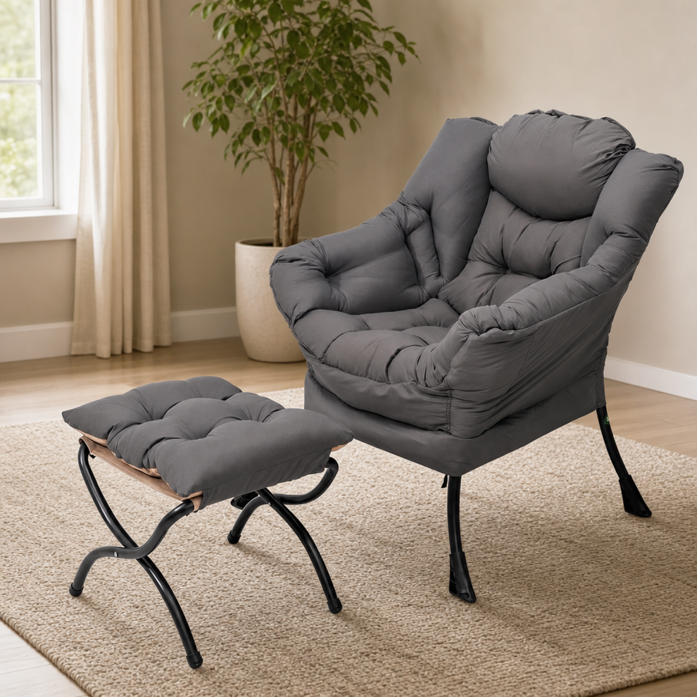 Dark grey padded lounge chair with matching ottoman angled front view in a bright living room
