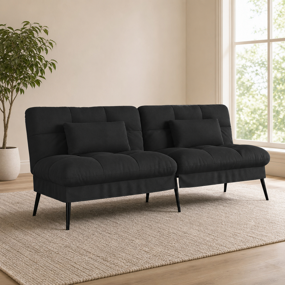 Black fabric futon sofa bed shown in upright sofa position, angled front view on a rug in a bright living room.