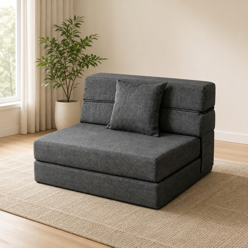 Dark grey folding futon sofa bed in compact sofa position with matching square pillow, angled front view