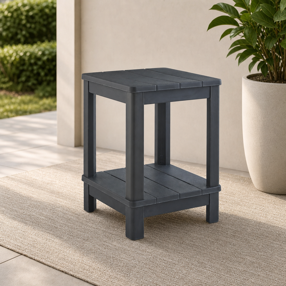 Graphite two-tier square outdoor side table on a patio rug with a planter nearby, angled front view